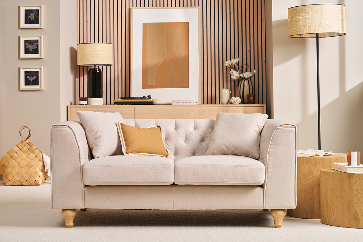 Canap� 2 places capitonn� beige avec coussins, vue de face.