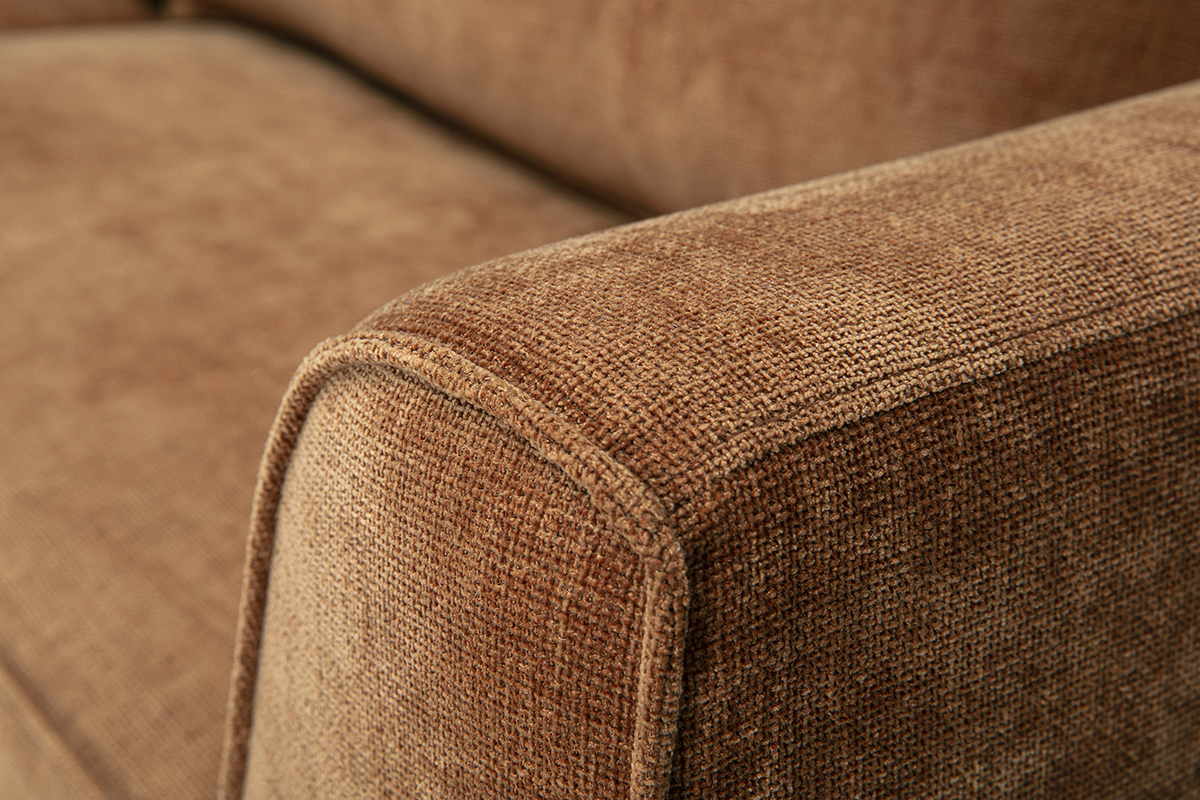 Gros plan d'un accoudoir de canap� en tissu effet velours textur� terre br�l�e.