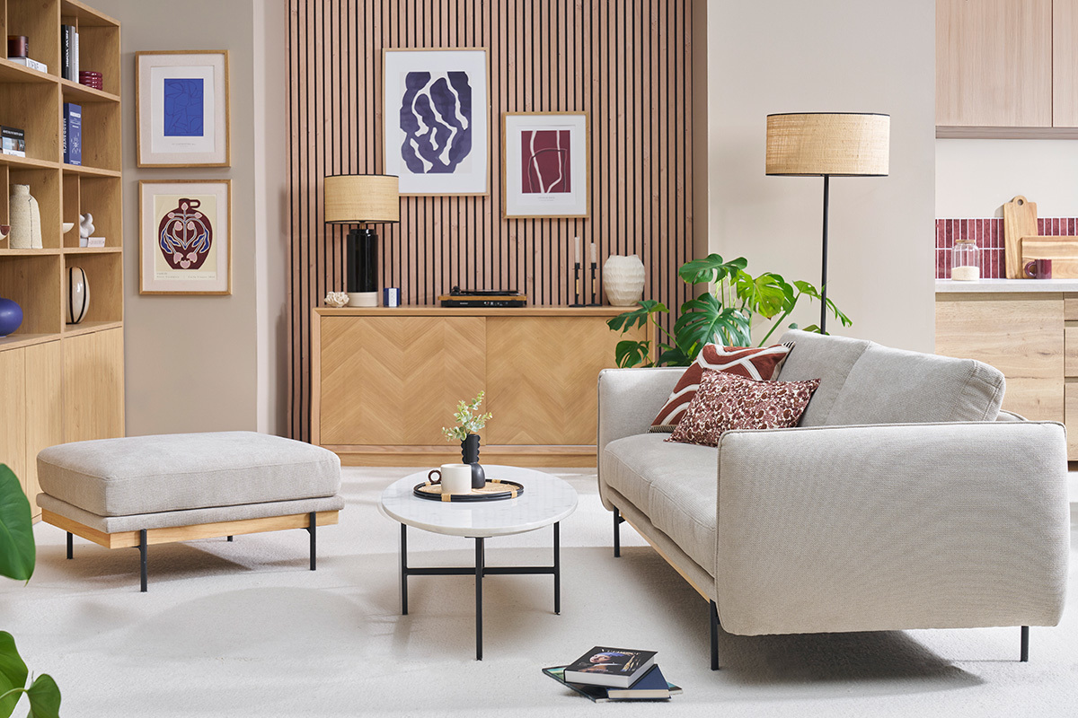 Pouf repose-pieds en tissu chenille beige, vue de face dans un salon moderne.