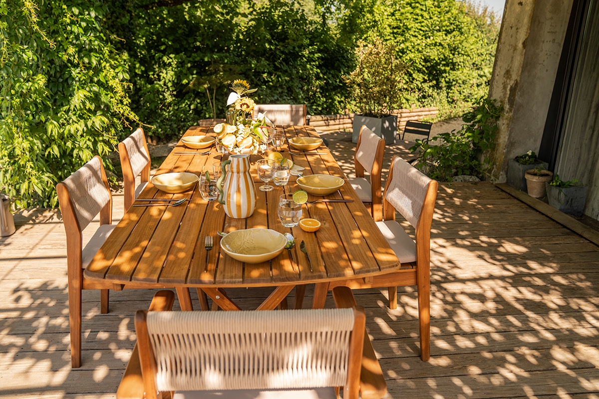 Table de jardin extensible en bois massif, vue de profil avec vaisselle, pr�te pour un repas en ext�rieur.